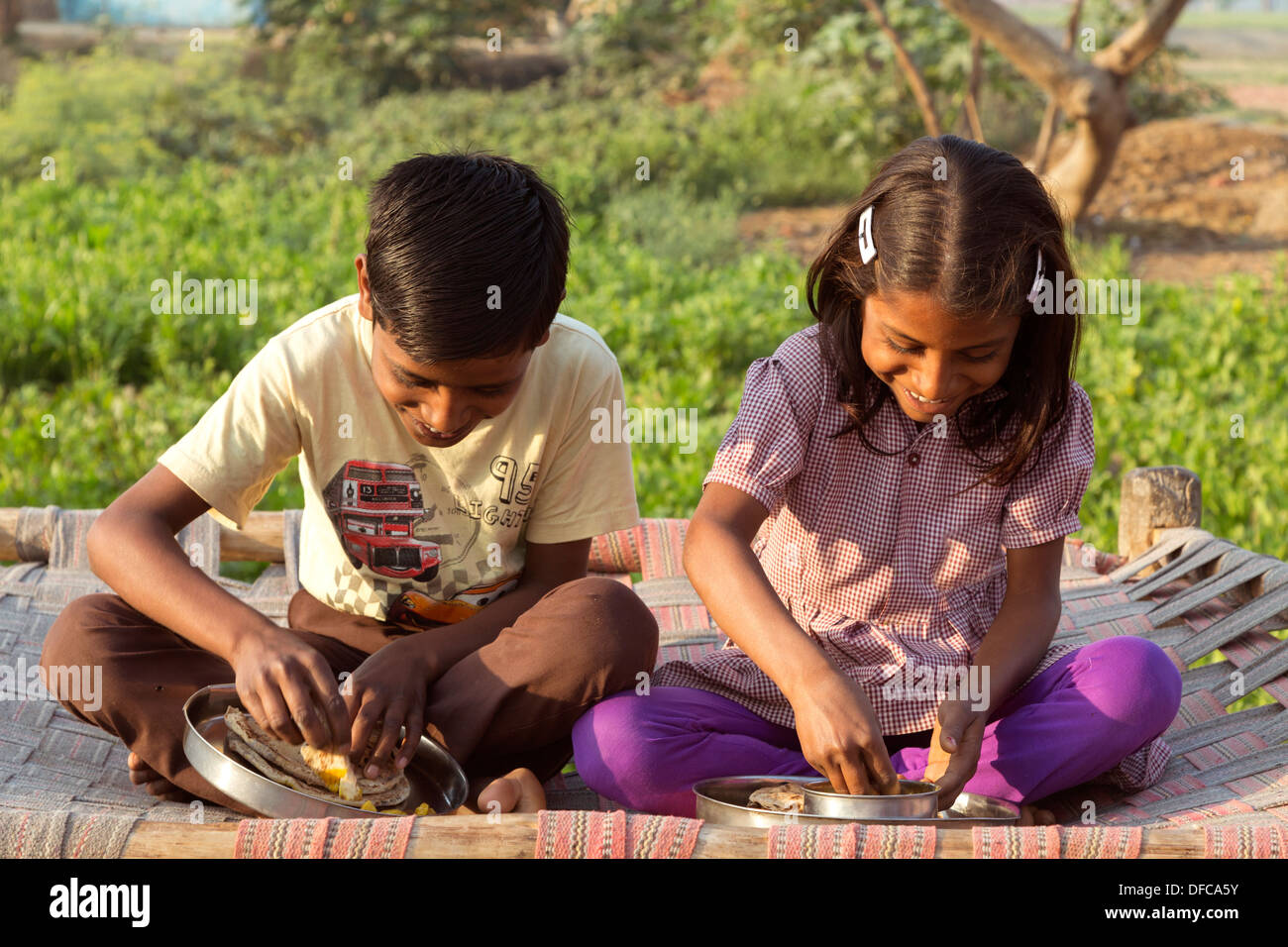 India, Uttar Pradesh, Agra, brother & sister eating traditional Indian breakfast of roti and curried potatoes, (aloo ghobi) Stock Photo