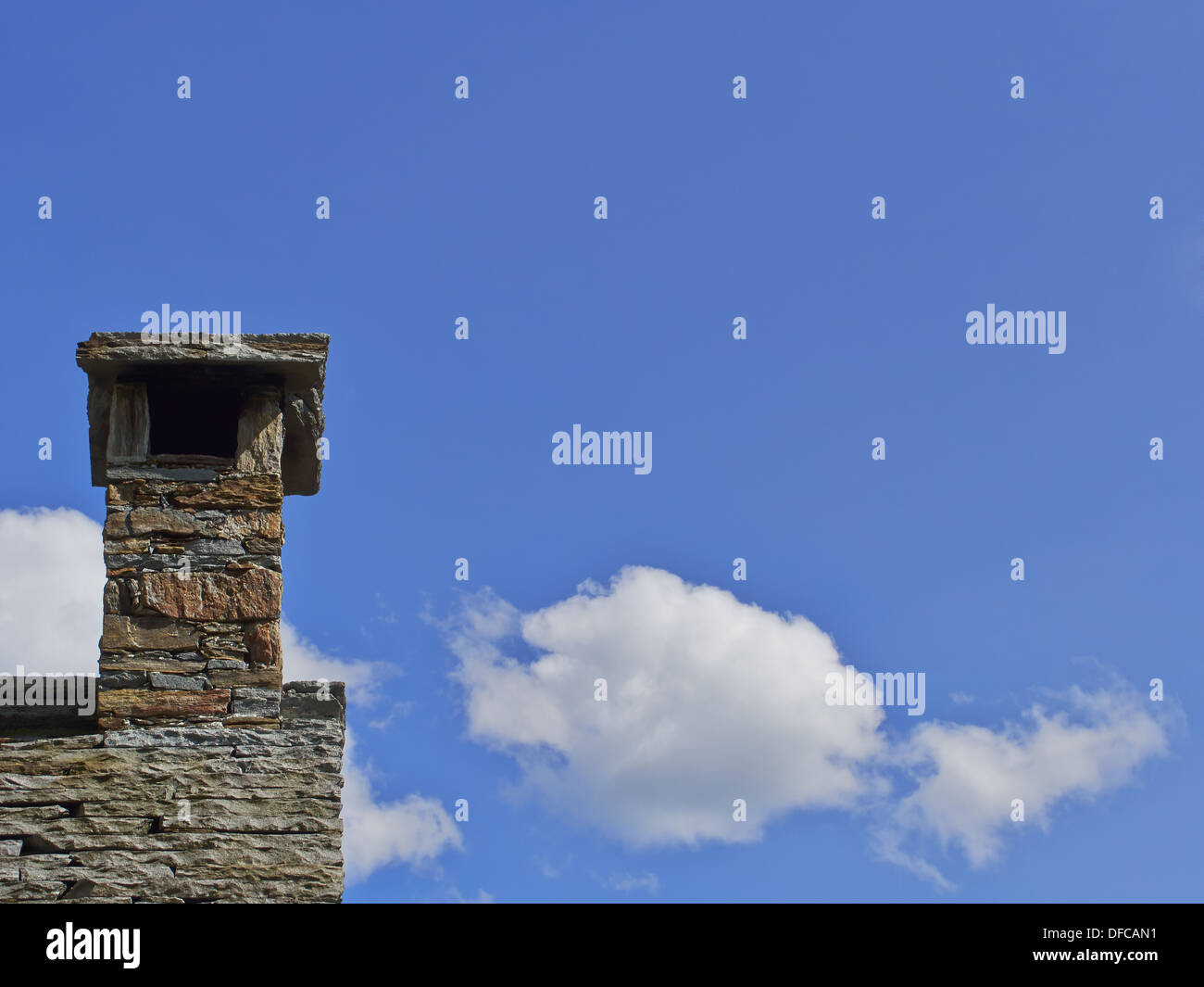 Chimney on an old slate roof with blue sky and some clouds Stock Photo