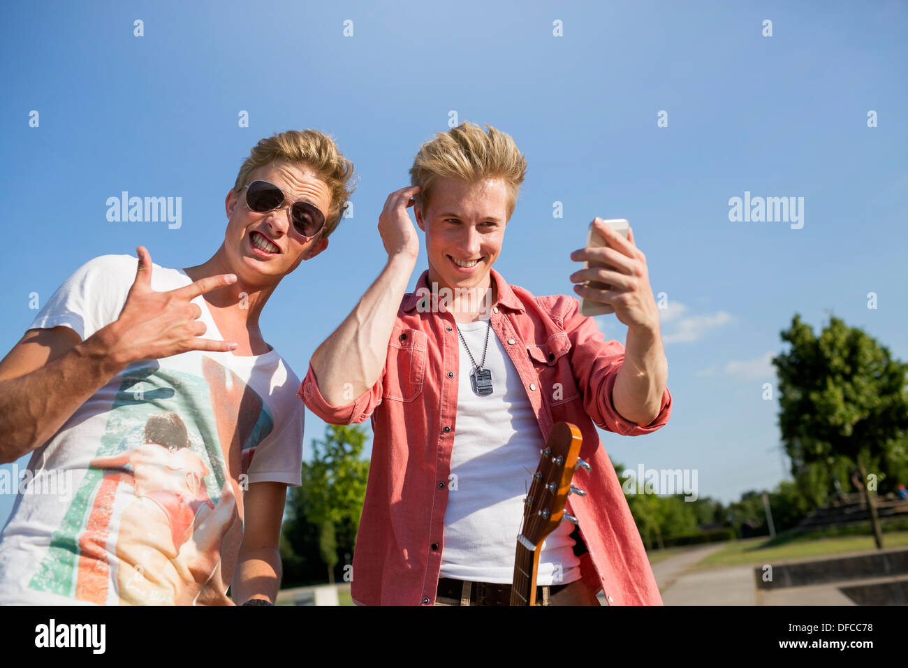 Germany, Young man is making rock' roll sigh, while friend is checking his looks Stock Photo