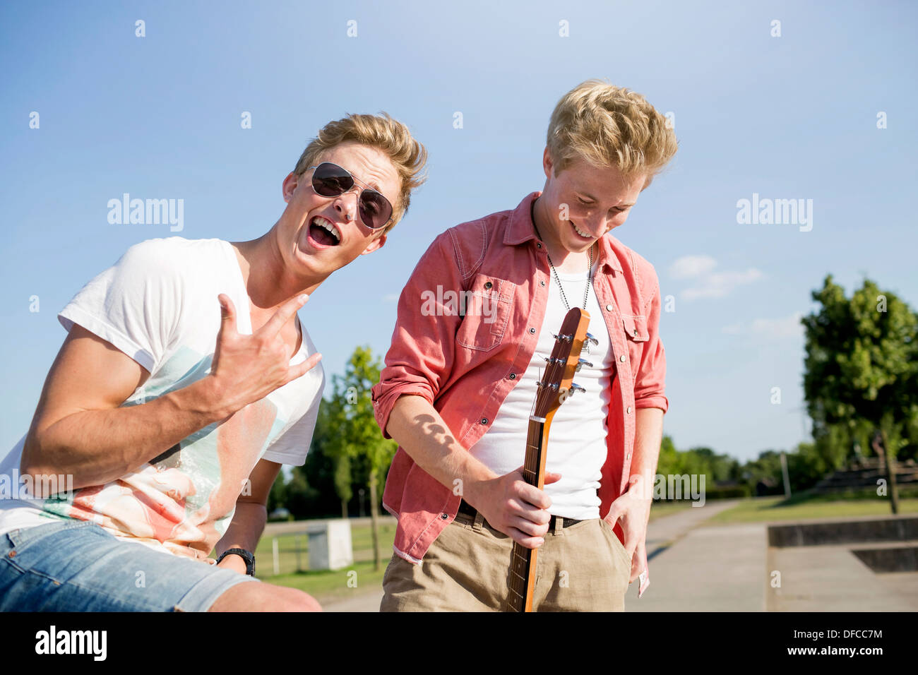 Germany, Young man is making rock' roll sigh, while friend is looking away Stock Photo
