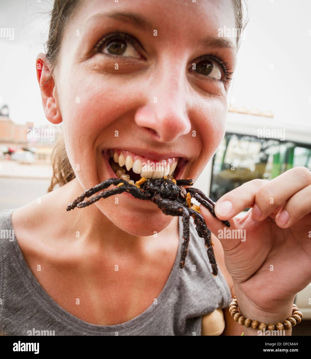 Cambodia, Young woman eating fried tarantula spiders Stock Photo