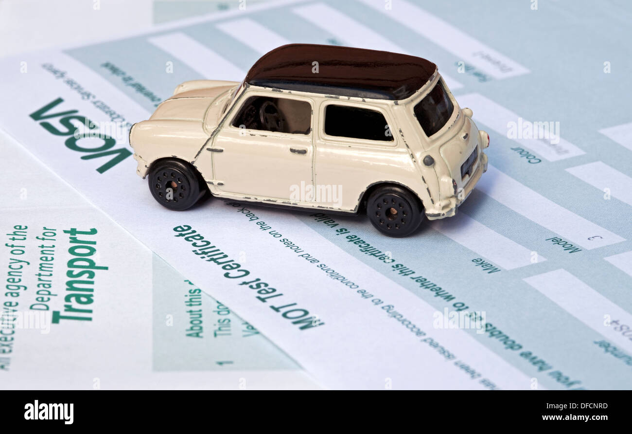 Close up of Children's old Mini Cooper toy car vehicle on MOT Test Certificate transport business motoring concept UK United Kingdom GB Great Britain Stock Photo