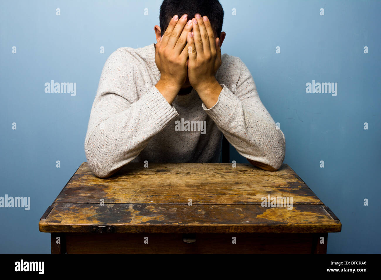 Upset man at desk is face palming Stock Photo