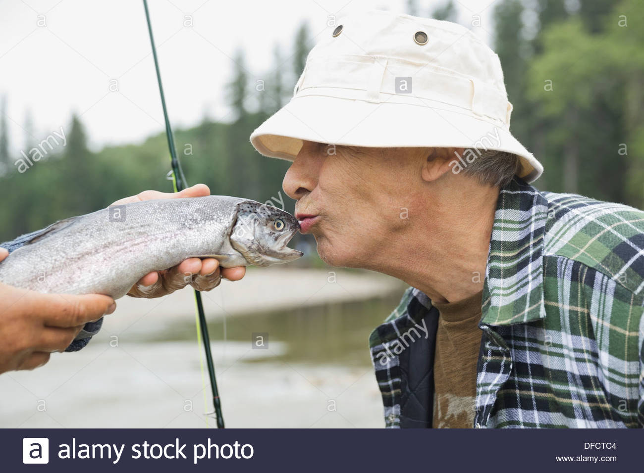 Side view of senior man kissing freshly caught fish Stock Photo