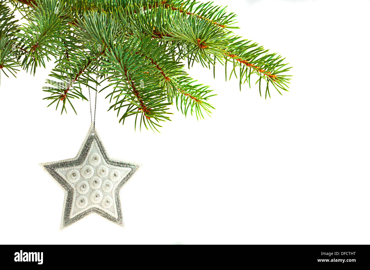 Silver star Christmas tree ornament hanging from a pine tree Stock Photo