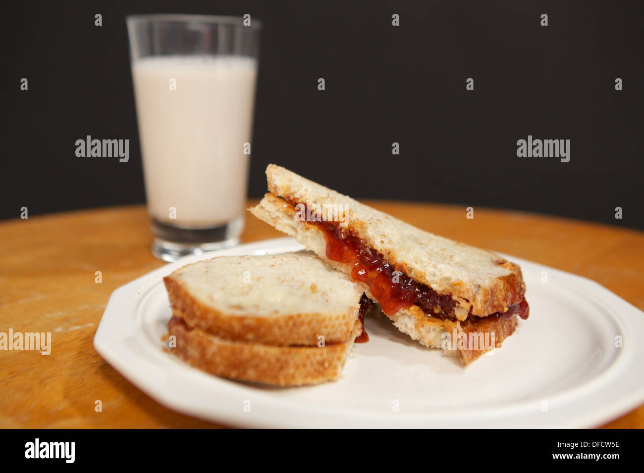 Peanut butter an jelly sandwich on sourdough bread with a glass of milk