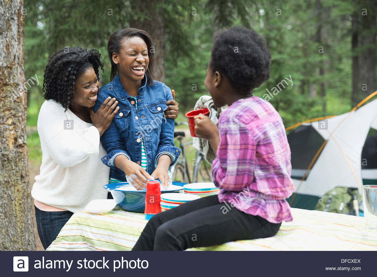 Cheerful mother and daughter washing dishes at campsite Stock Photo Alamy