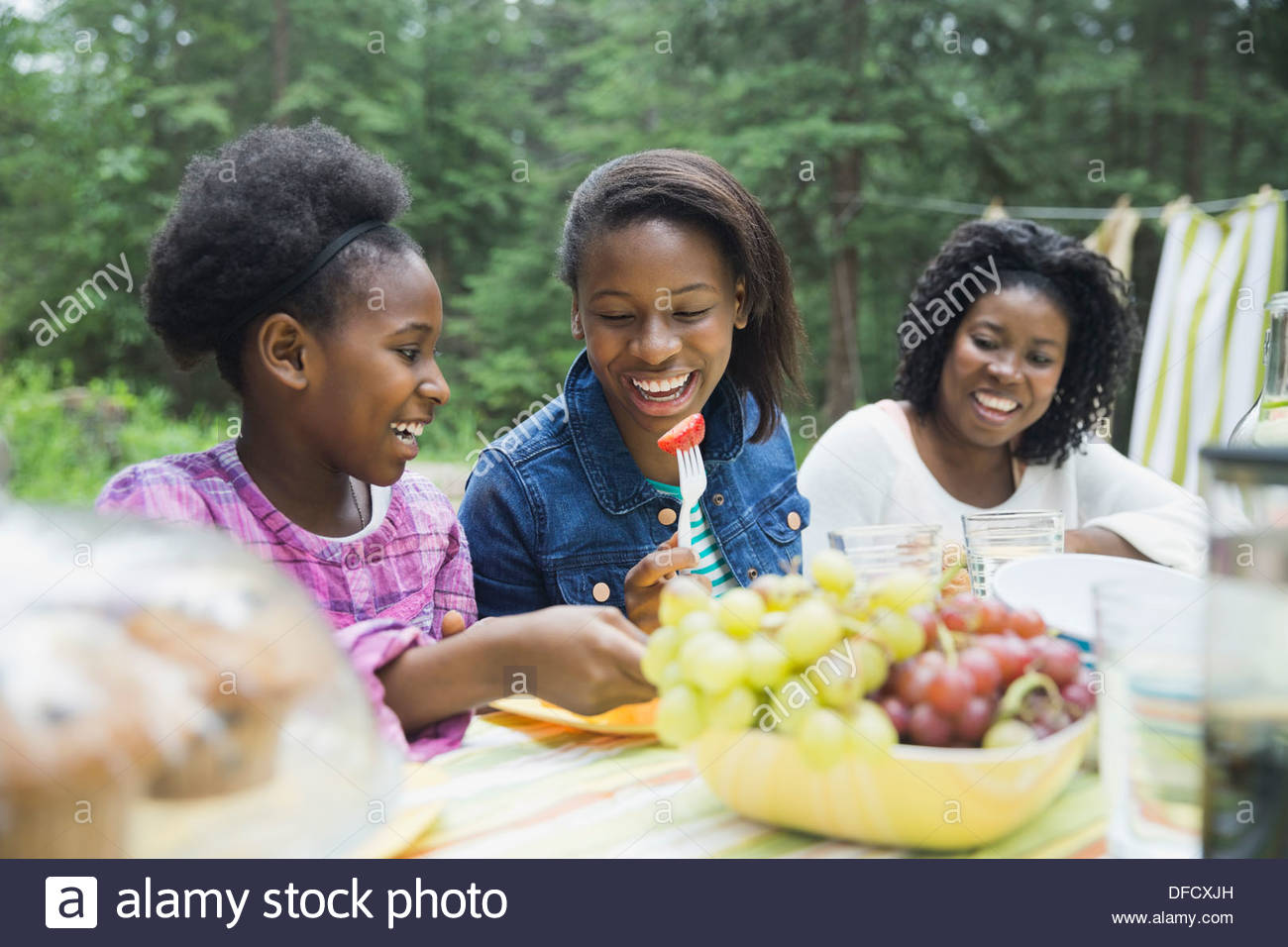 Cheerful siblings having meal with mother at campsite Stock Photo