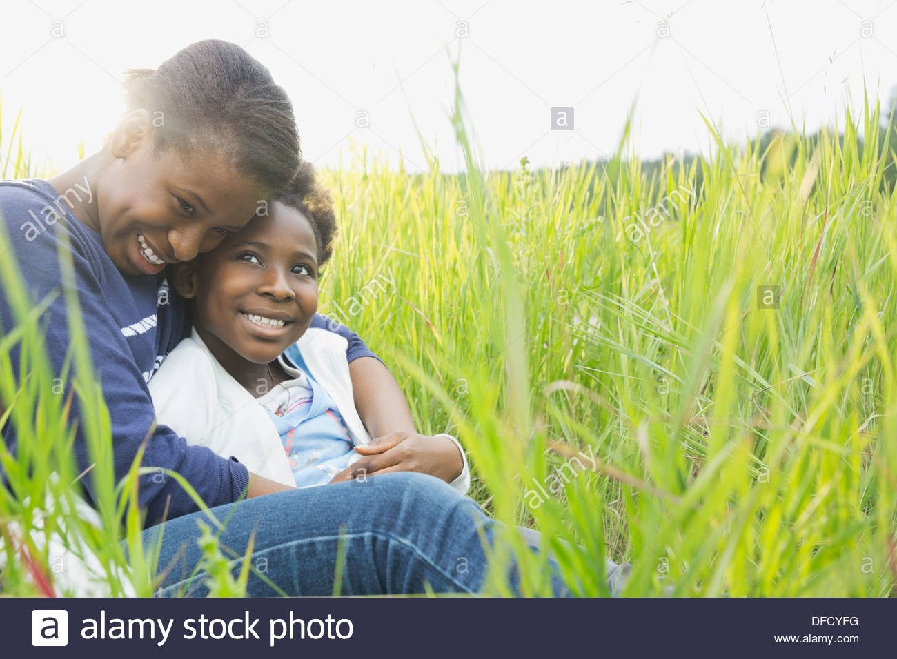 Loving sisters embracing in field Stock Photo