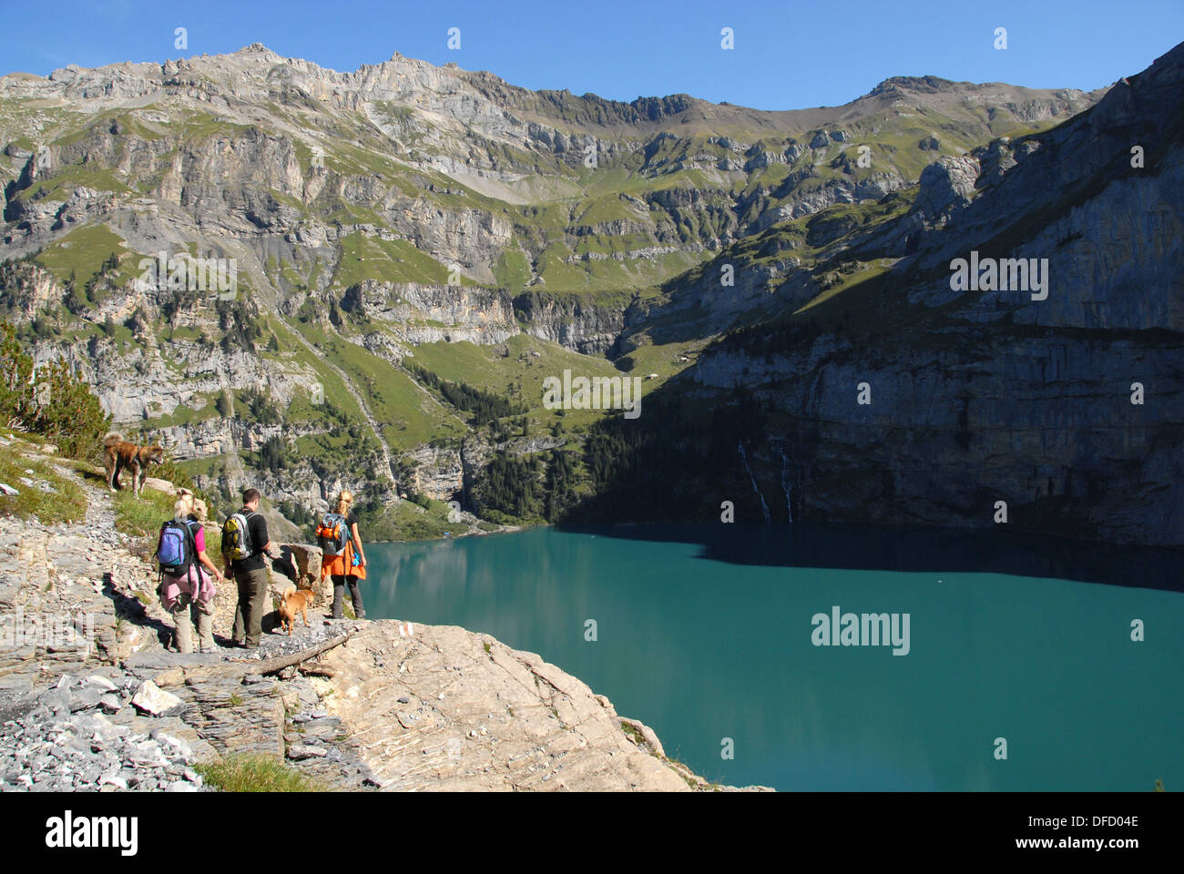 Hikers on Heuberg trail above Oeschinen lake above Kandersteg, Bernese alps, Switzerland Stock Photo