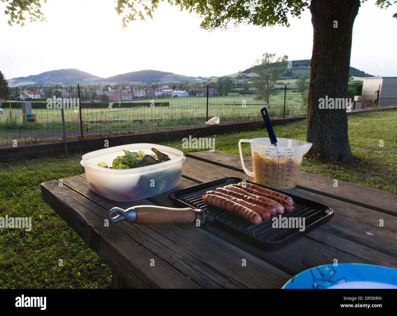 simple campsite meal of couscous and sausages cooked on a griddle with salad leaves in Haute-Loire, France Stock Photo