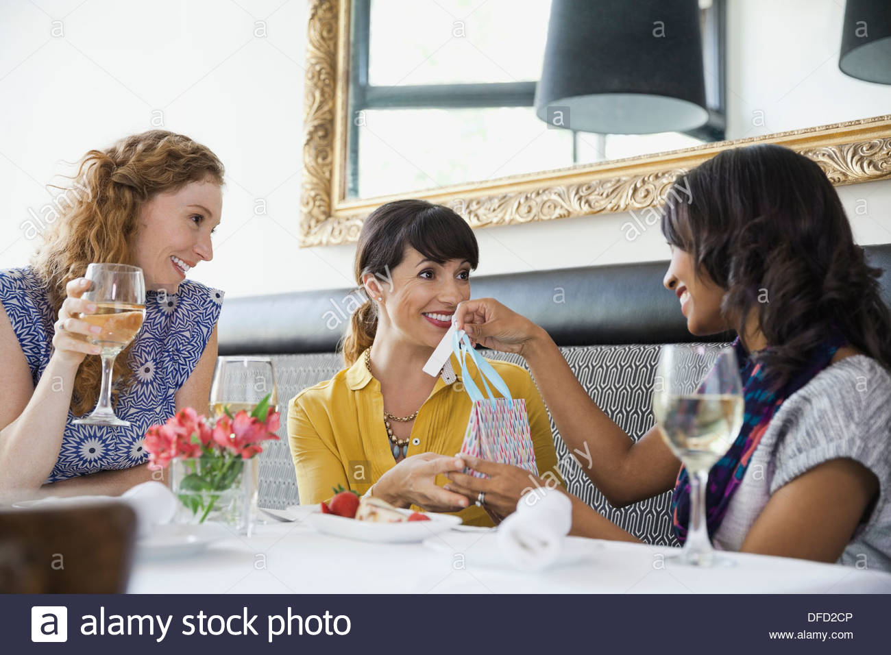Woman giving gift bag to female friend in restaurant Stock Photo