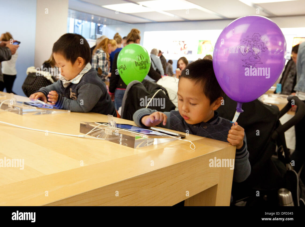 Apple store interior; Children playing with iPads inside the Apple