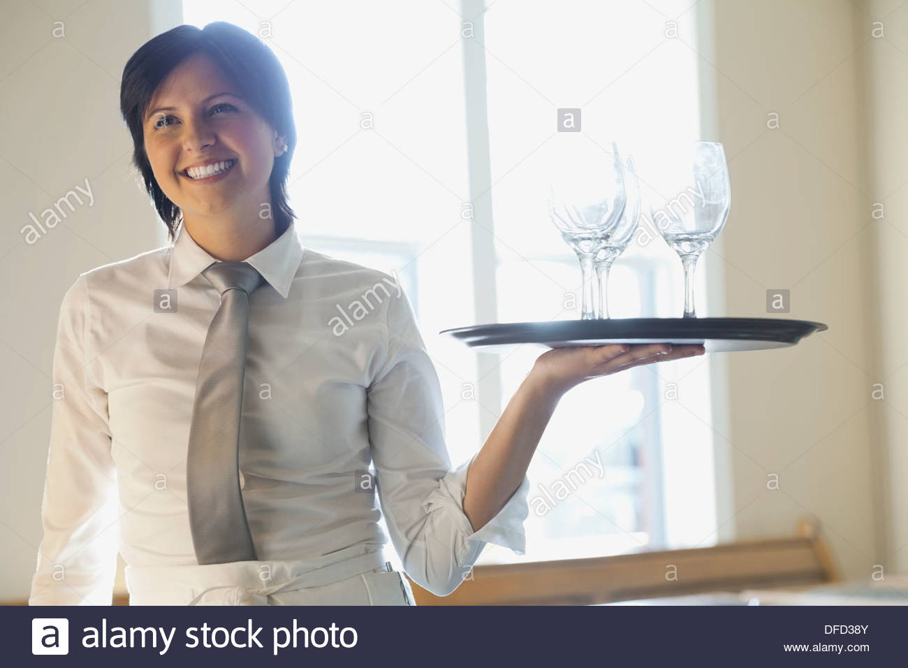 Waitress carrying tray of wine glasses in restaurant Stock Photo