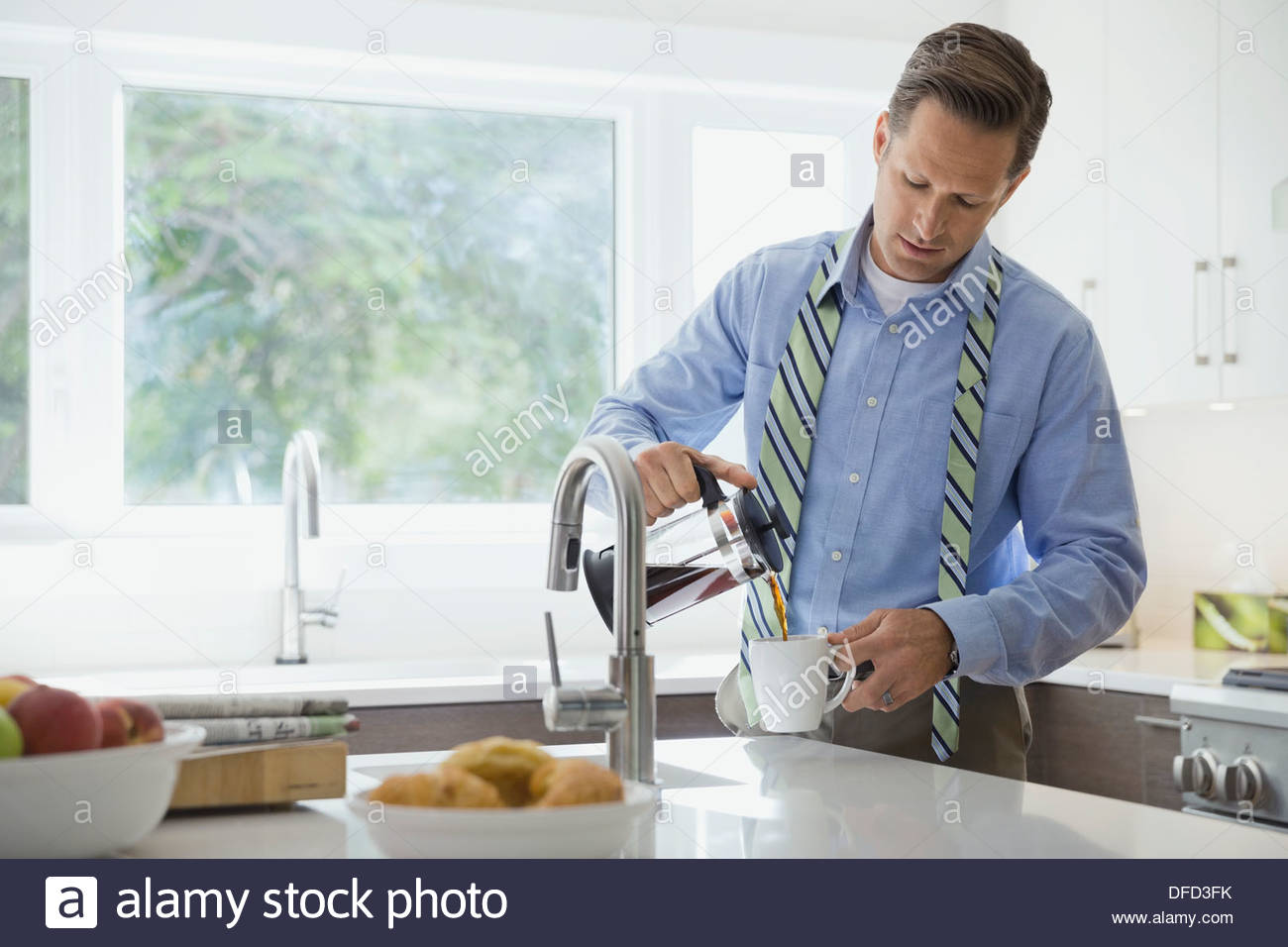Businessman pouring coffee in domestic kitchen Stock Photo