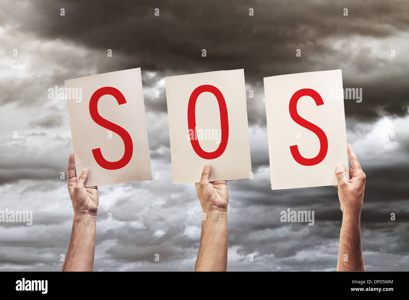 SOS message, save our souls. Human hands holding papers with printed letters SOS. Stock Photo