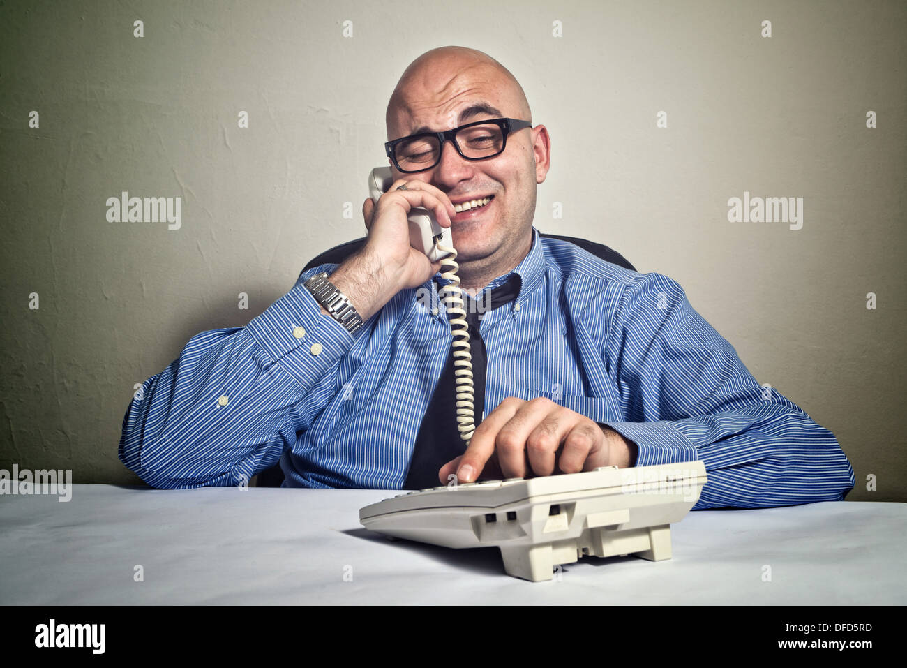 Smiling businessman at office desk with telephone. Wheeler dealer or business crook. Stock Photo