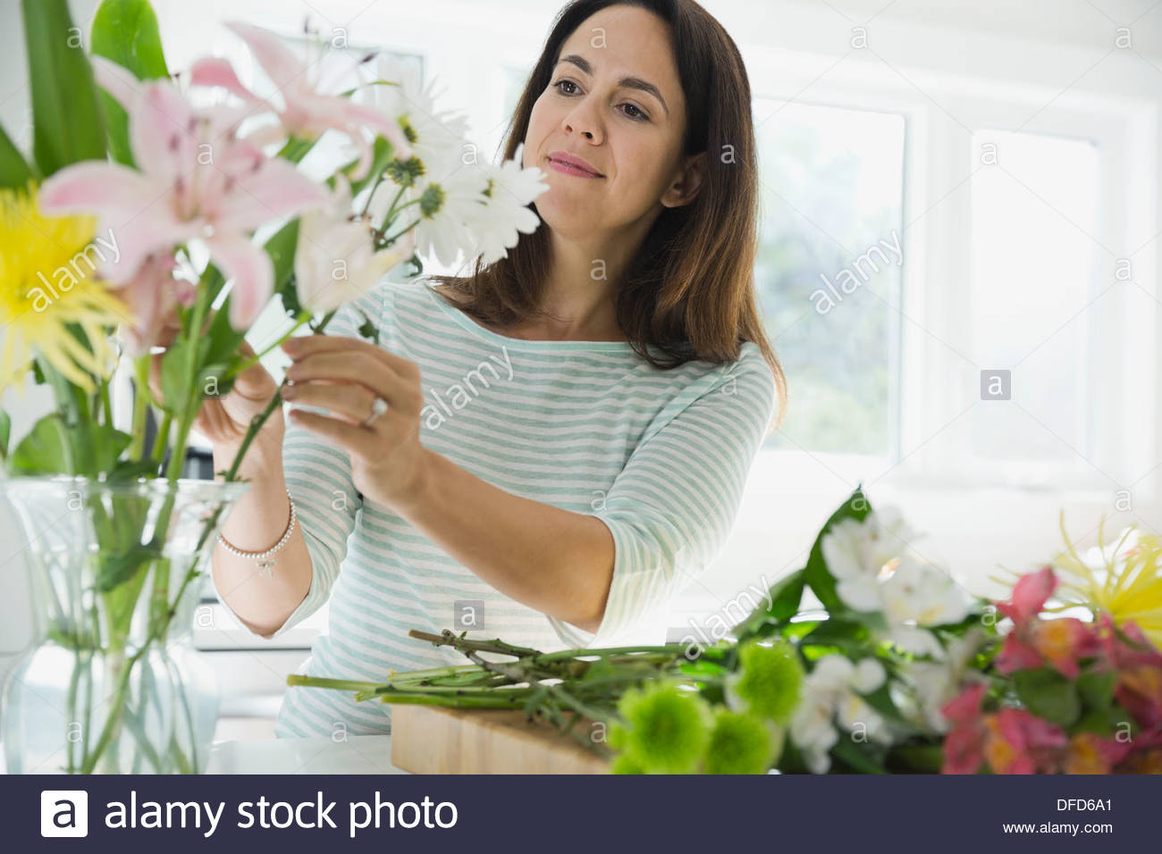Woman arranging flowers in vase at home Stock Photo
