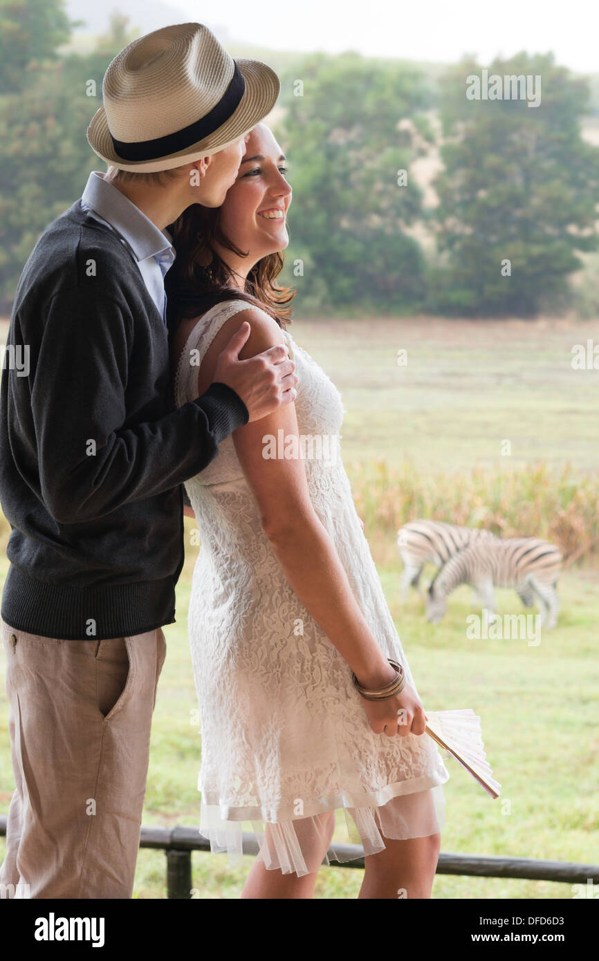 Couple in late twenties on honeymoon watching zebras in pasture, Winelands, Western Cape, Stellenbosch, South Africa Stock Photo