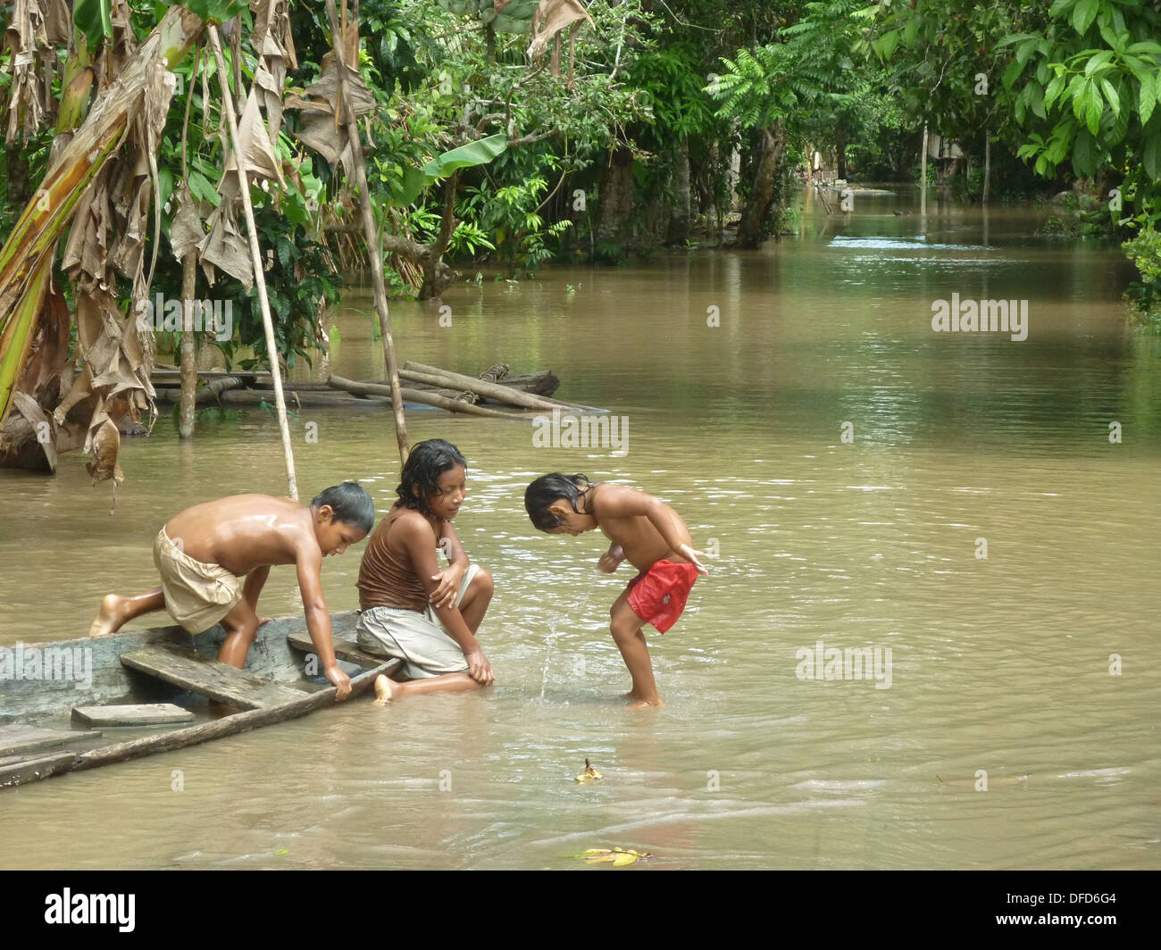 Children of the Yagua Tribe play with a wooden canoe in the Amazon rain forest near Iquitos, Peru Stock Photo