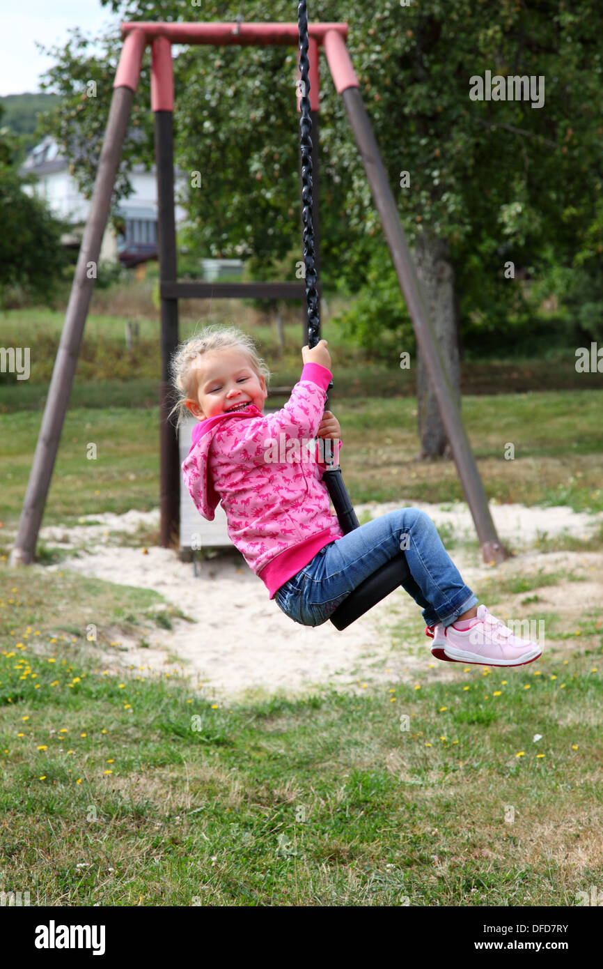 Happy toddler girl on a swing in city park Stock Photo