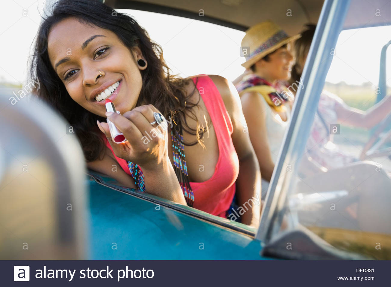 Woman applying lipstick in rear view mirror Stock Photo