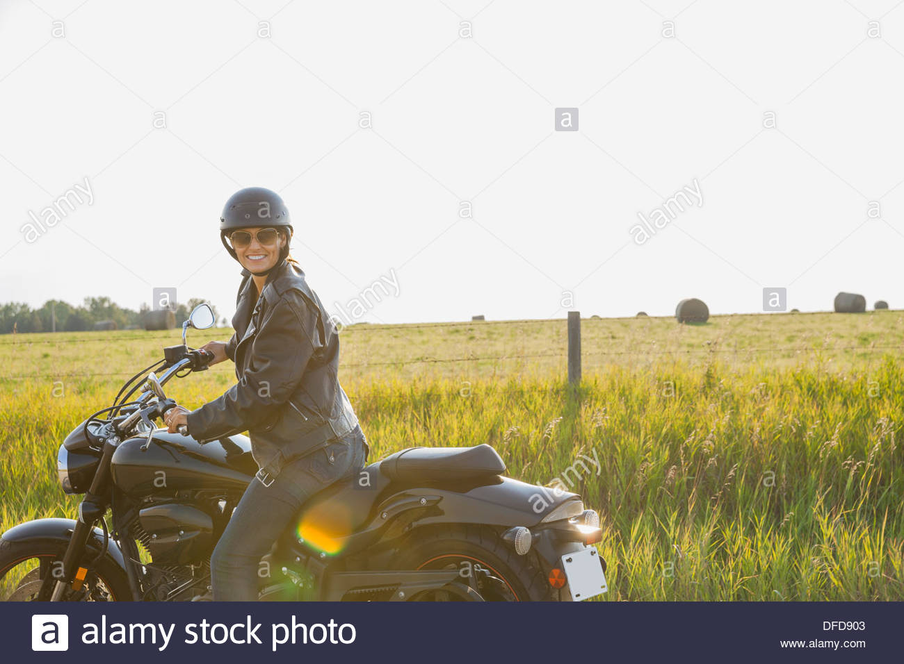 Portrait of female biker sitting on motorcycle Stock Photo