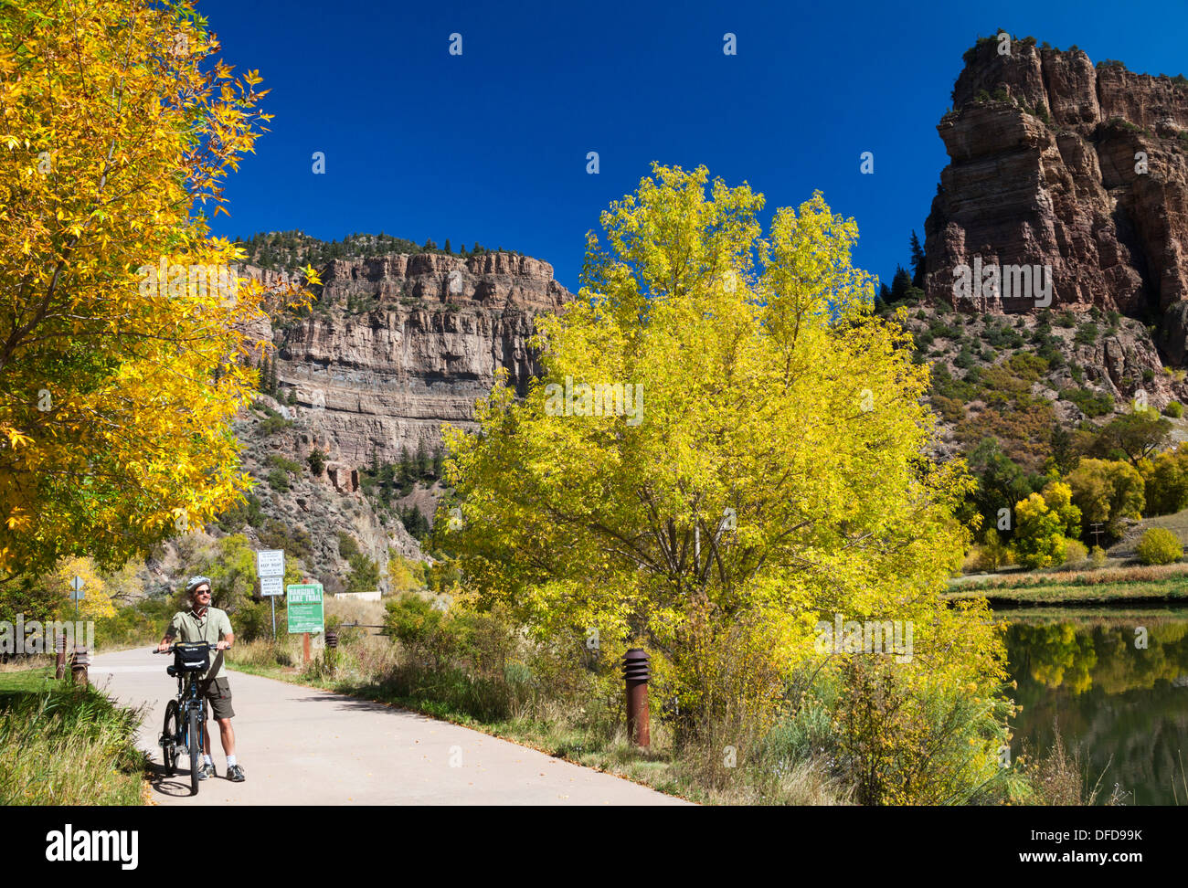 Bicyclist in autumn near the Colorado River at the Hanging Lake rest area along the bike path in Glenwood Canyon in Colorado Stock Photo
