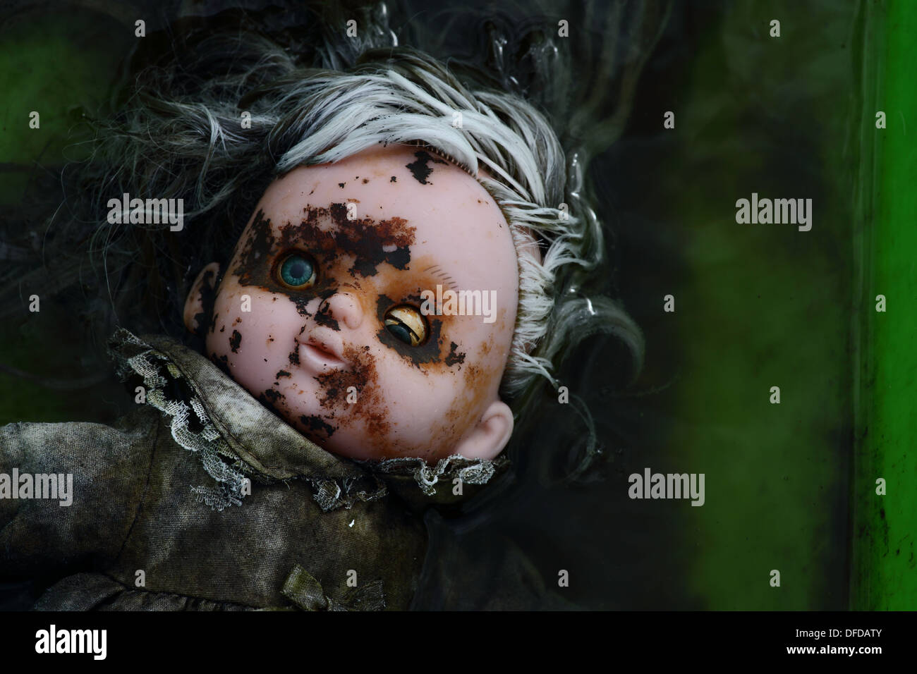 A broken doll falling to pieces while floating in a bath of water Stock Photo