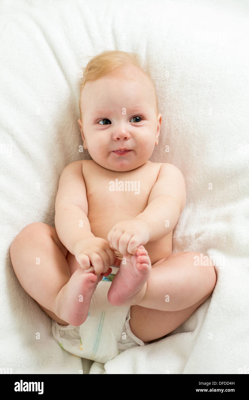 baby boy lying on white sheet and holding his legs Stock Photo Alamy
