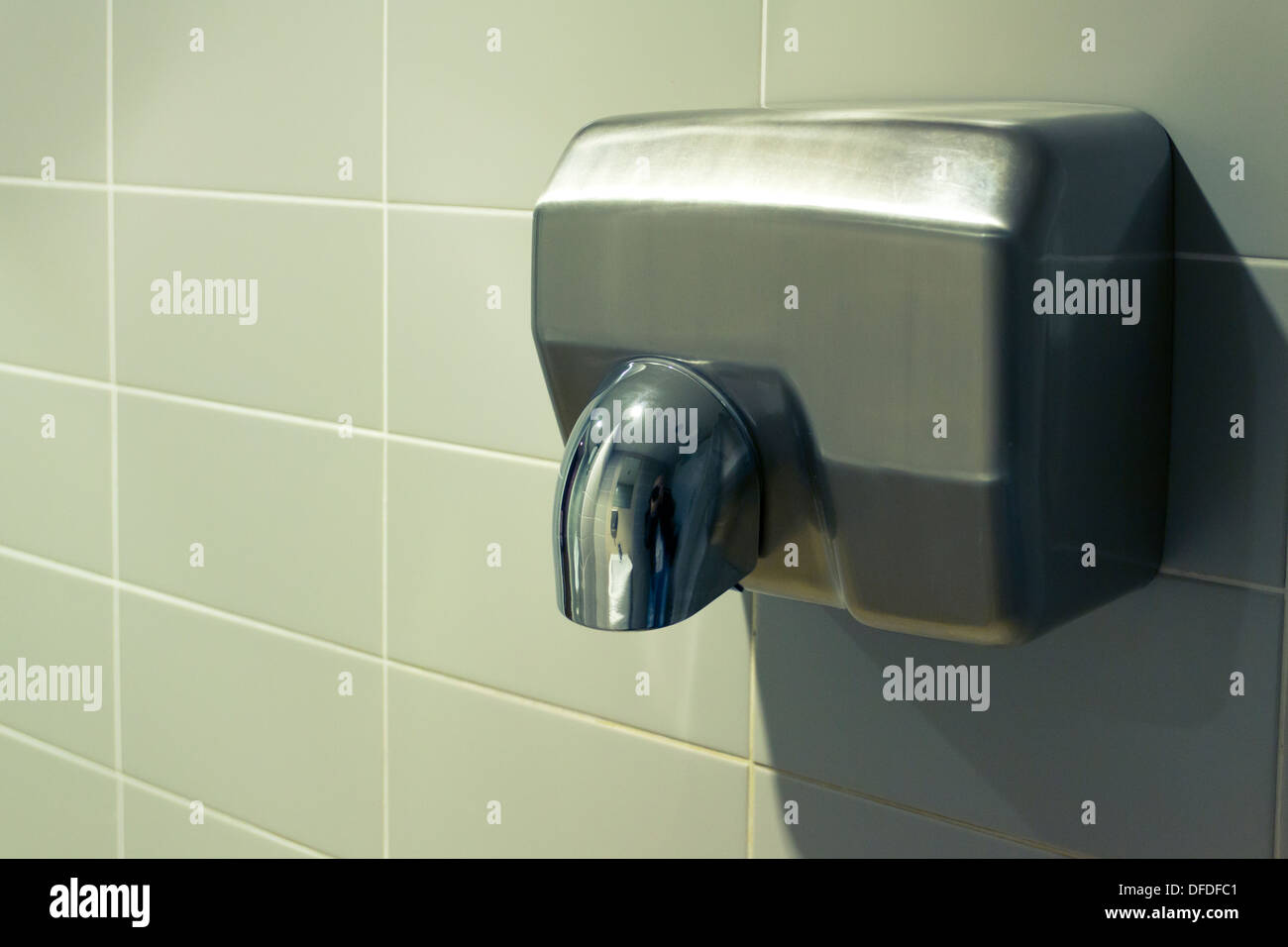 Silver hand dryer on a grey tiled wall Stock Photo