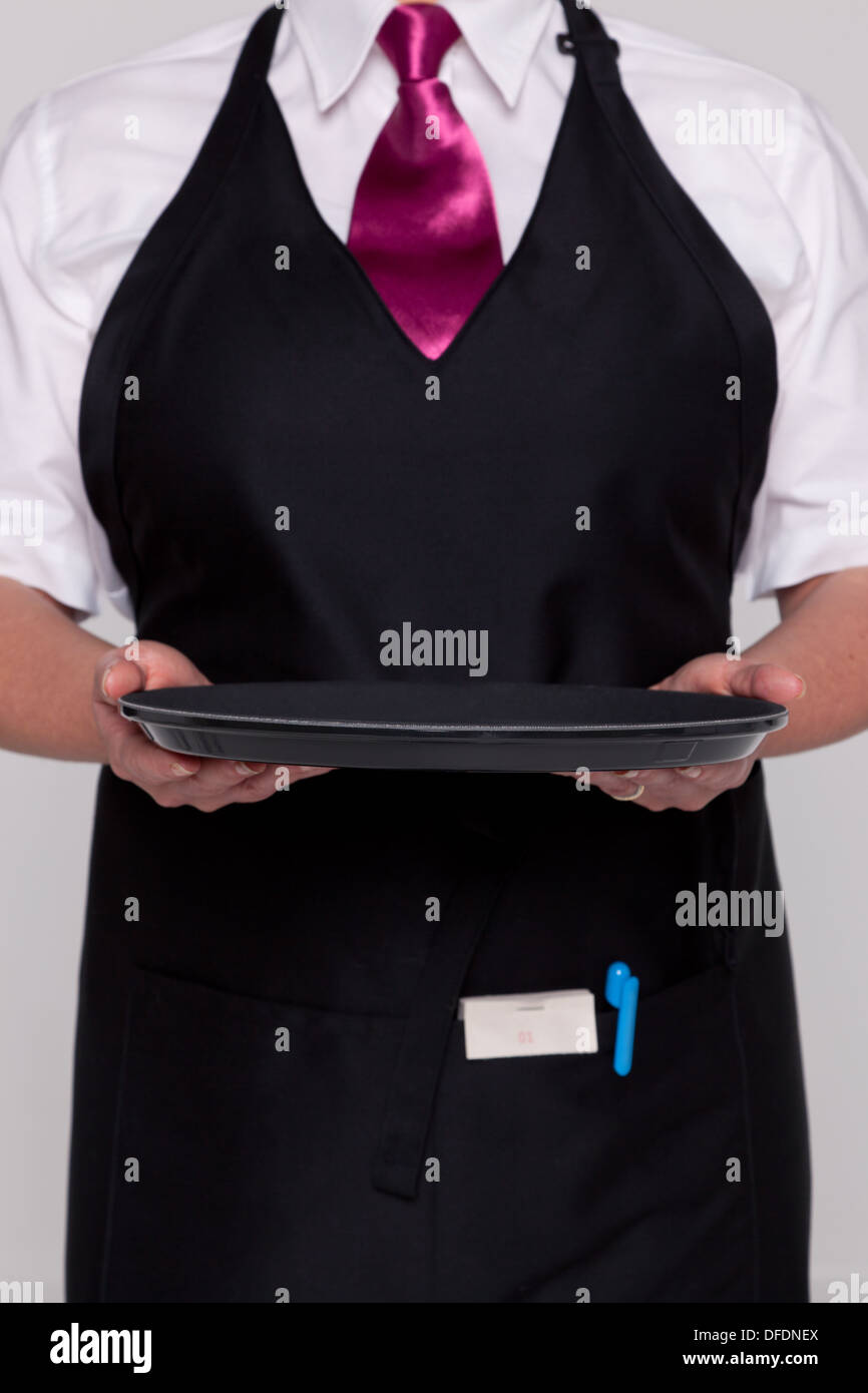 A waitress wearing an apron and tie holding an empty tray. Good image for product placement.. Stock Photo