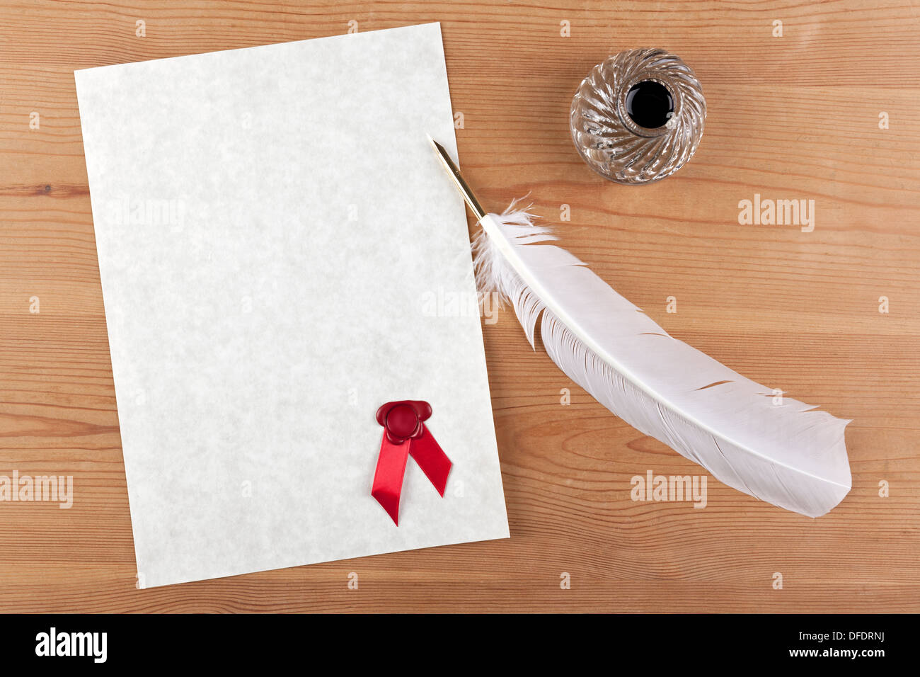 A blank piece of parchment paper with red wax seal, plus feather quill and glass ink well on a desk Stock Photo