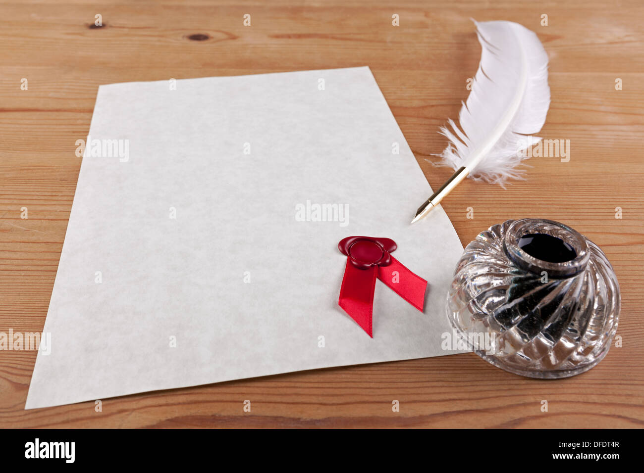 A blank piece of parchment paper with red wax seal, plus feather quill and glass ink well on a desk, Stock Photo