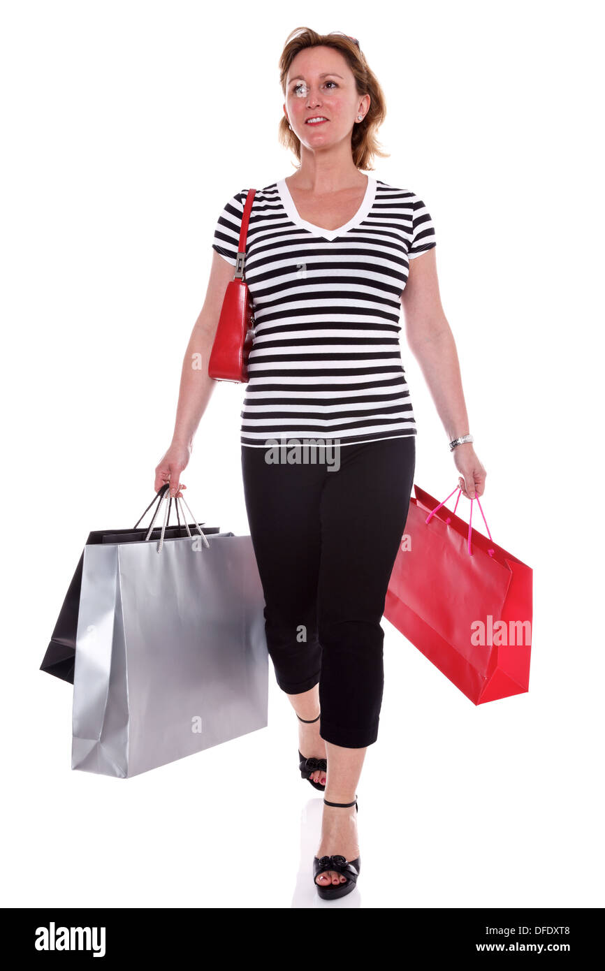 A woman in designer clothing carrying shopping bags, isolated on a white background. Stock Photo