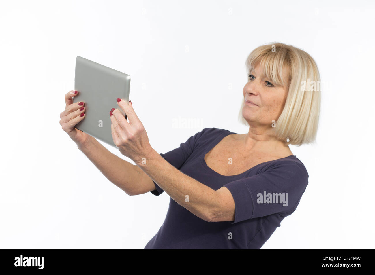 Senior woman using a tablet computer photographed in studio on white background Stock Photo
