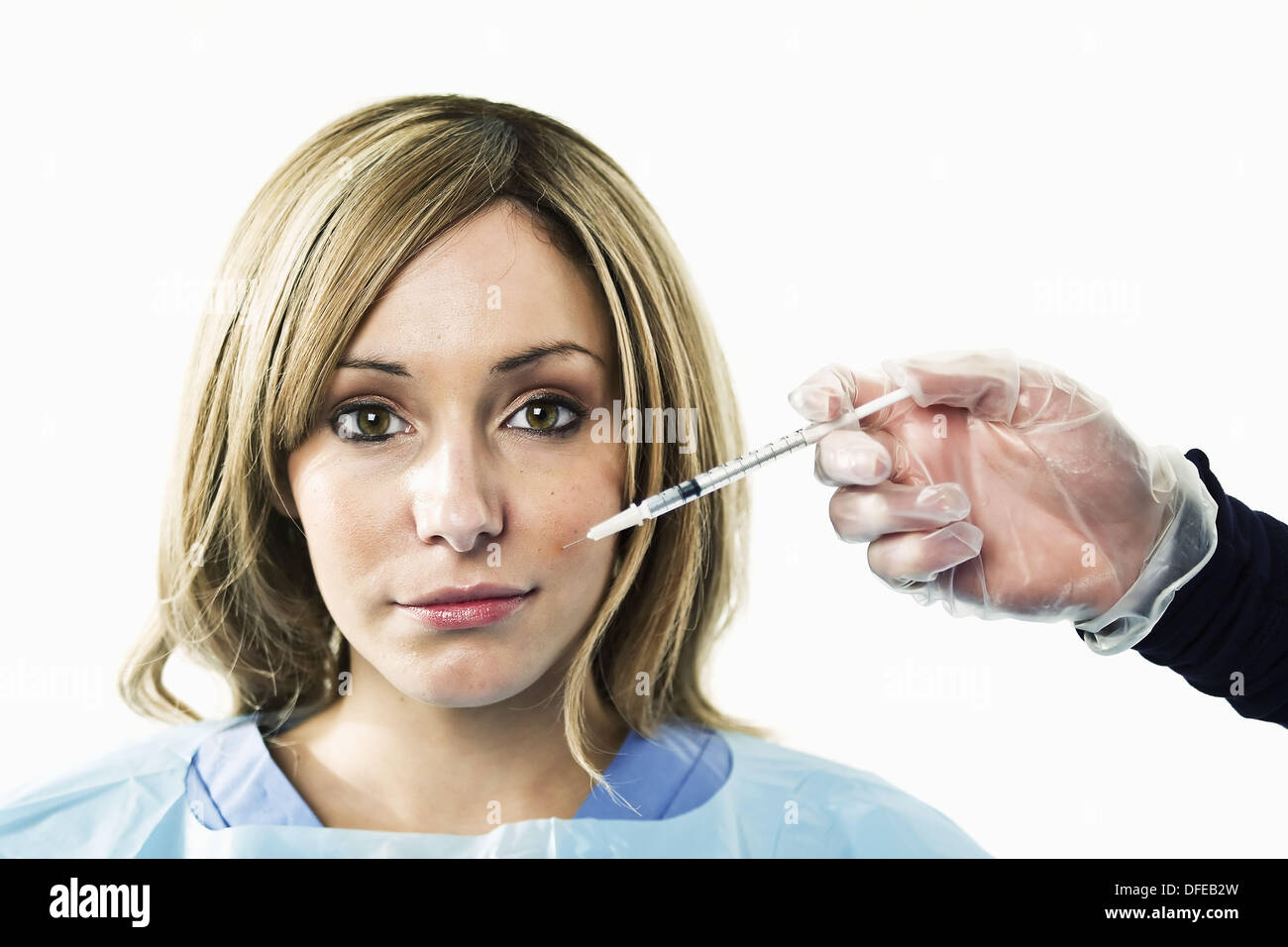 A young woman is injected with a syringe containing botox Stock Photo