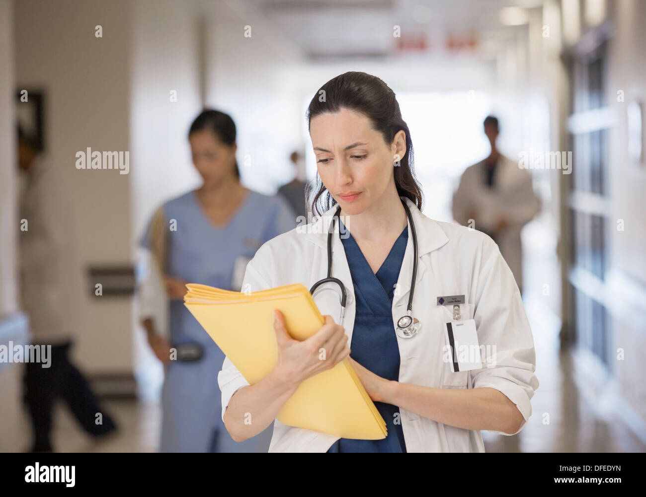 Doctor looking down at folder in hospital corridor Stock Photo