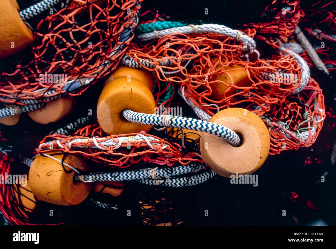 Closeup of fishing net with orange floats laying on the ground in ...