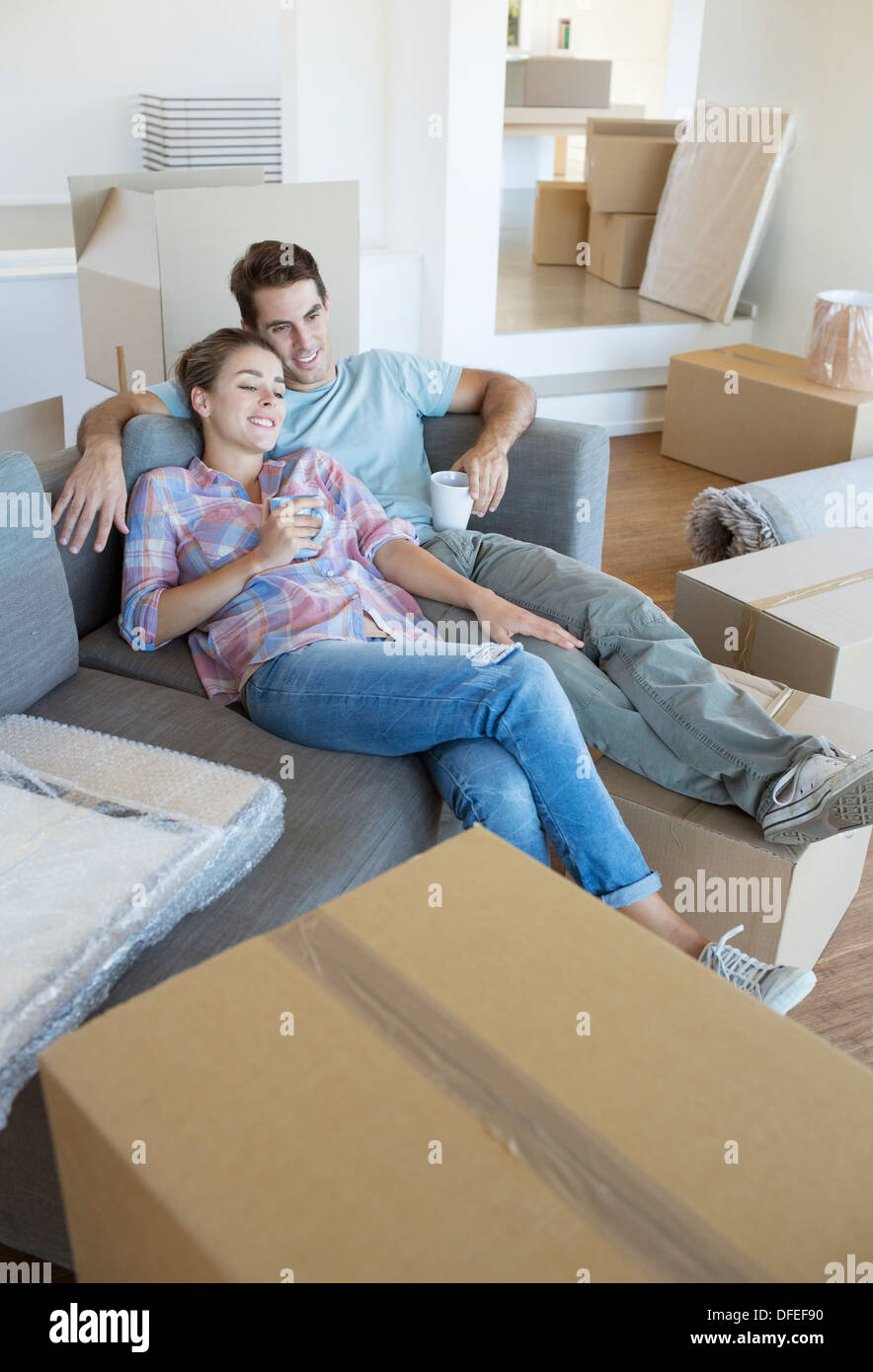Couple relaxing with coffee on sofa in new house Stock Photo