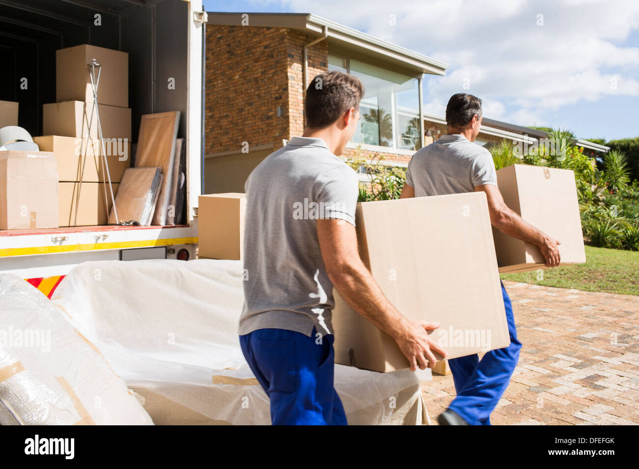 Movers carrying boxes in new house Stock Photo