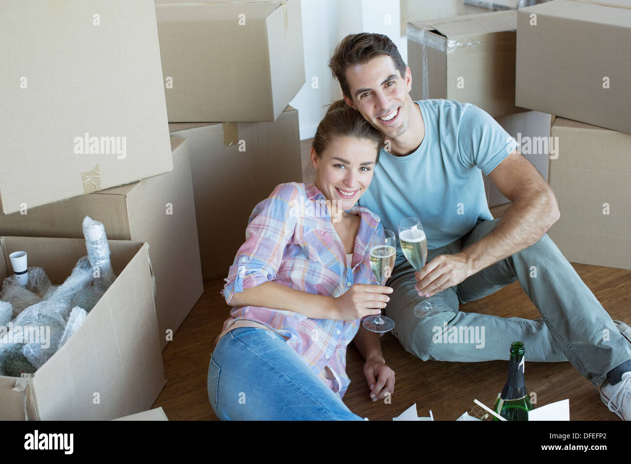 Portrait of couple enjoying champagne among cardboard boxes Stock Photo
