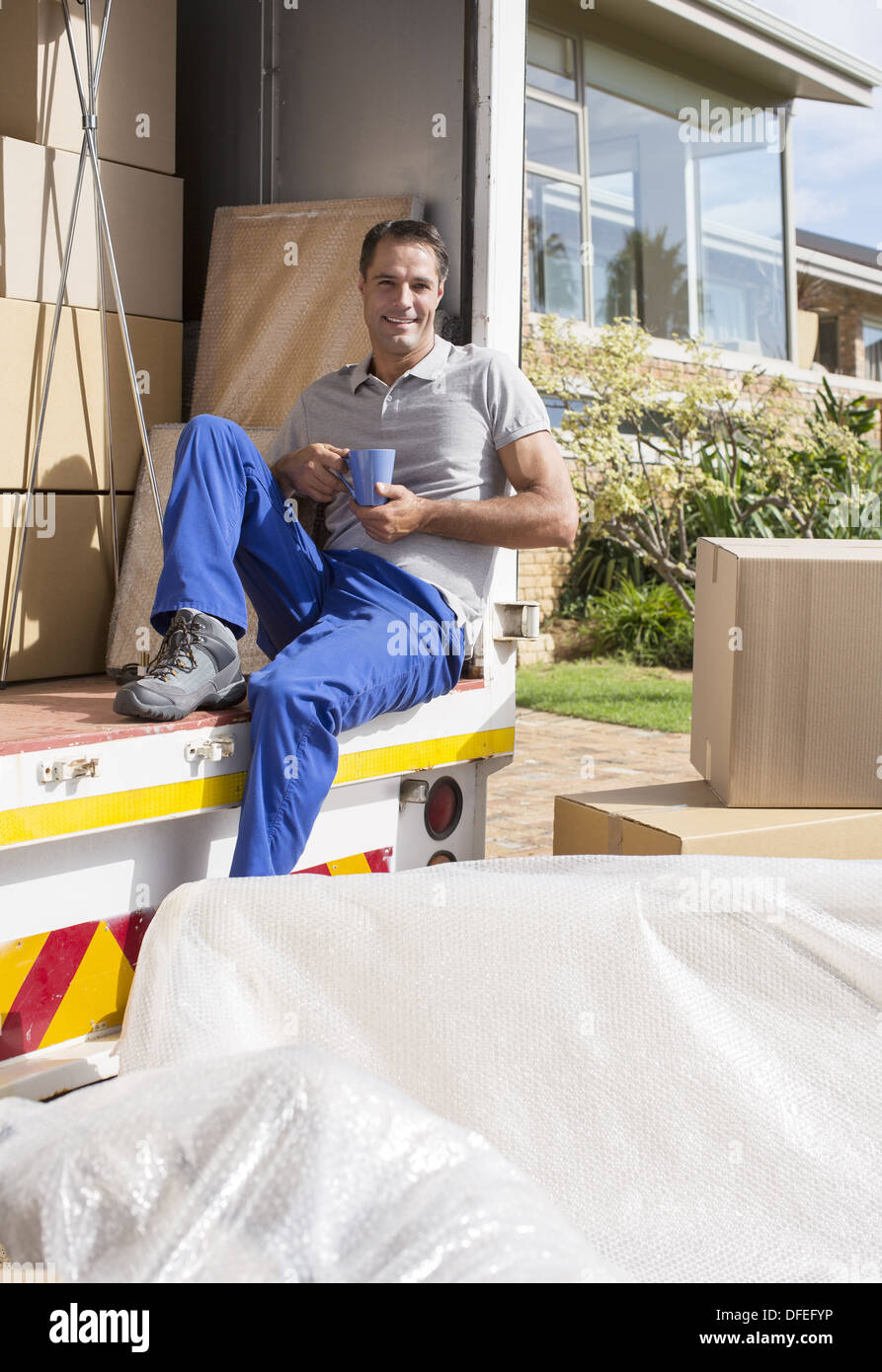 Mover enjoying cup of coffee in back of moving van Stock Photo