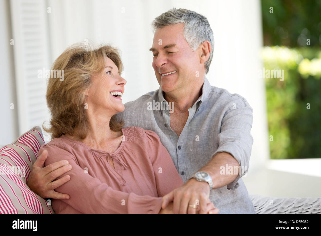 Senior couple hugging in armchair on patio Stock Photo