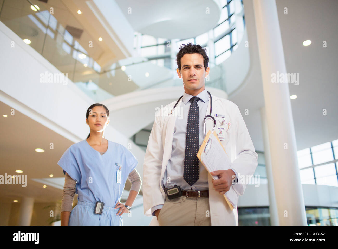 Portrait of confident doctor and nurse in hospital atrium Stock Photo