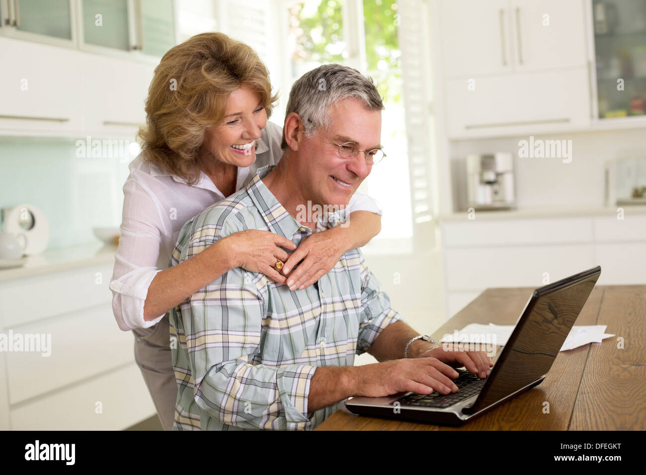 Senior couple using laptop in kitchen Stock Photo
