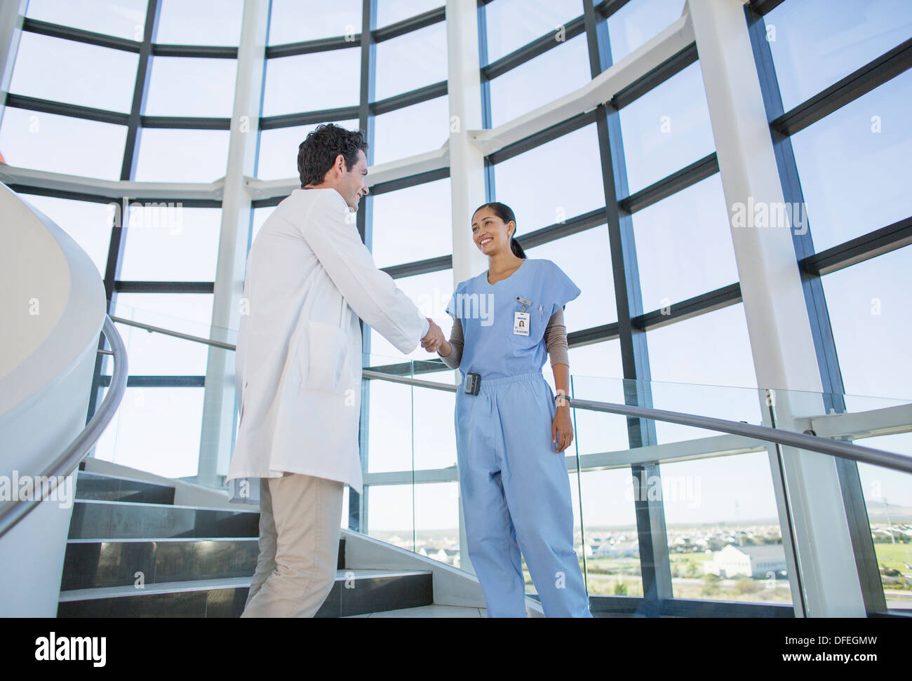 Doctor and nurse handshaking on hospital staircase Stock Photo