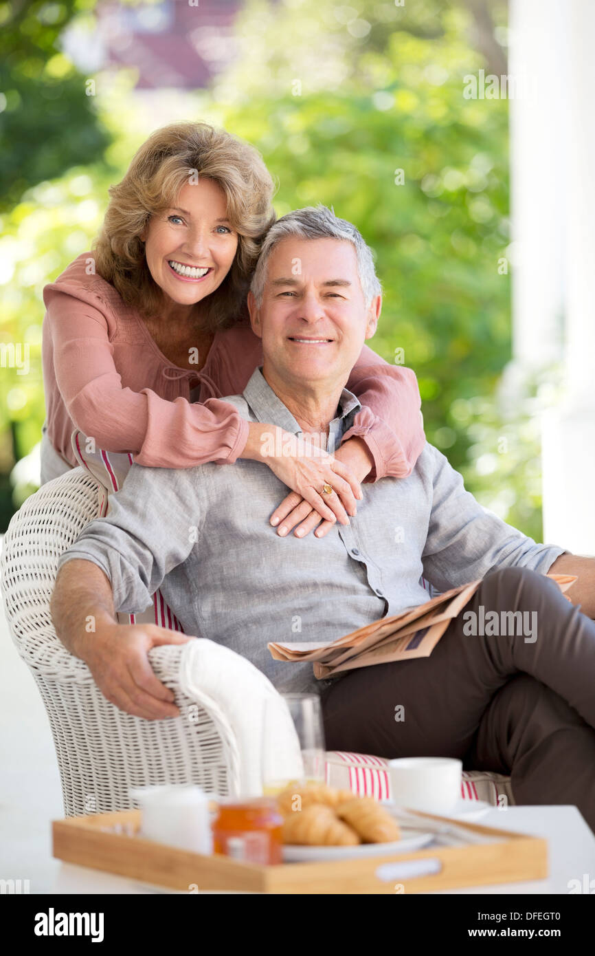 Portrait of smiling senior couple hugging on patio Stock Photo