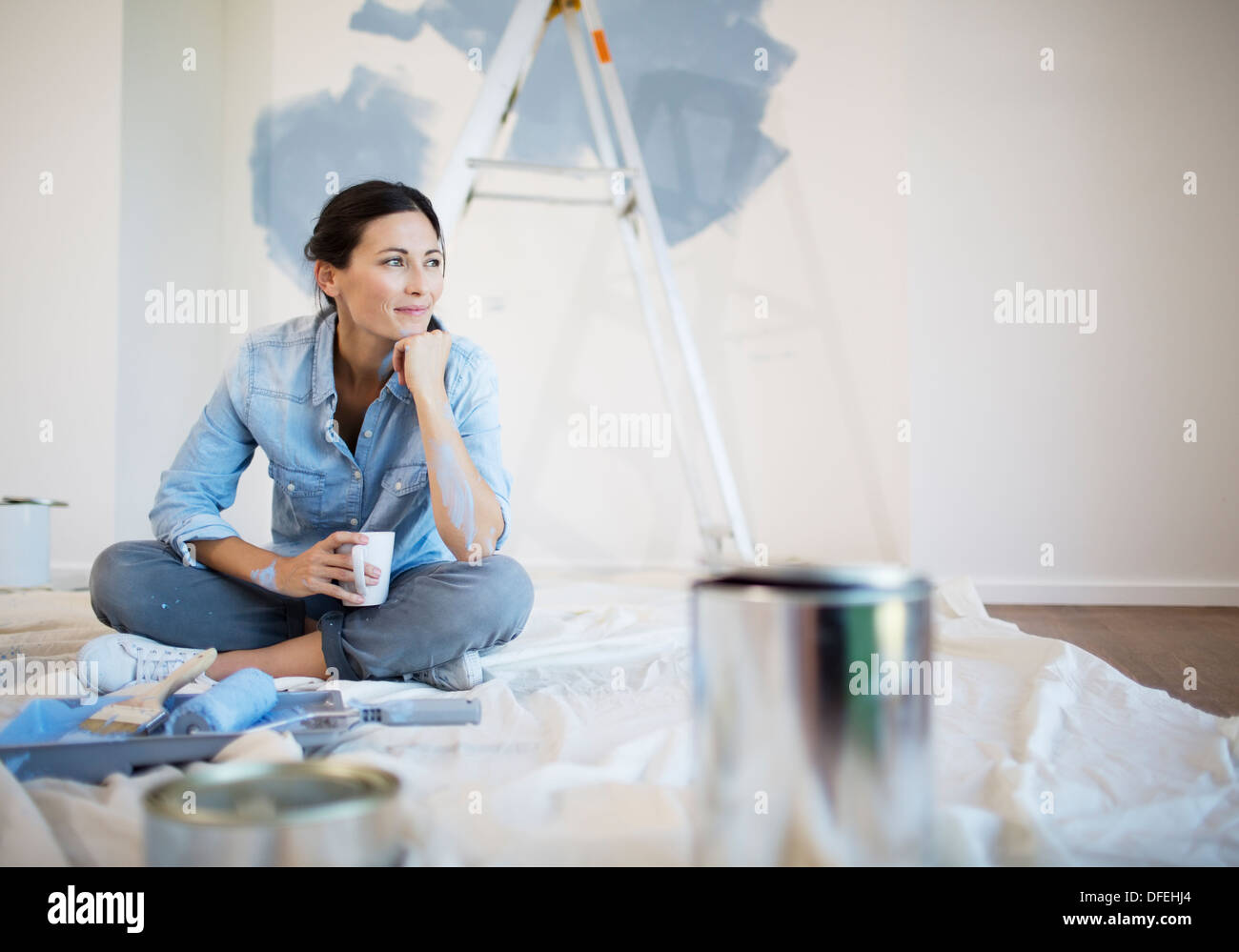 Woman relaxing with coffee among painting supplies Stock Photo