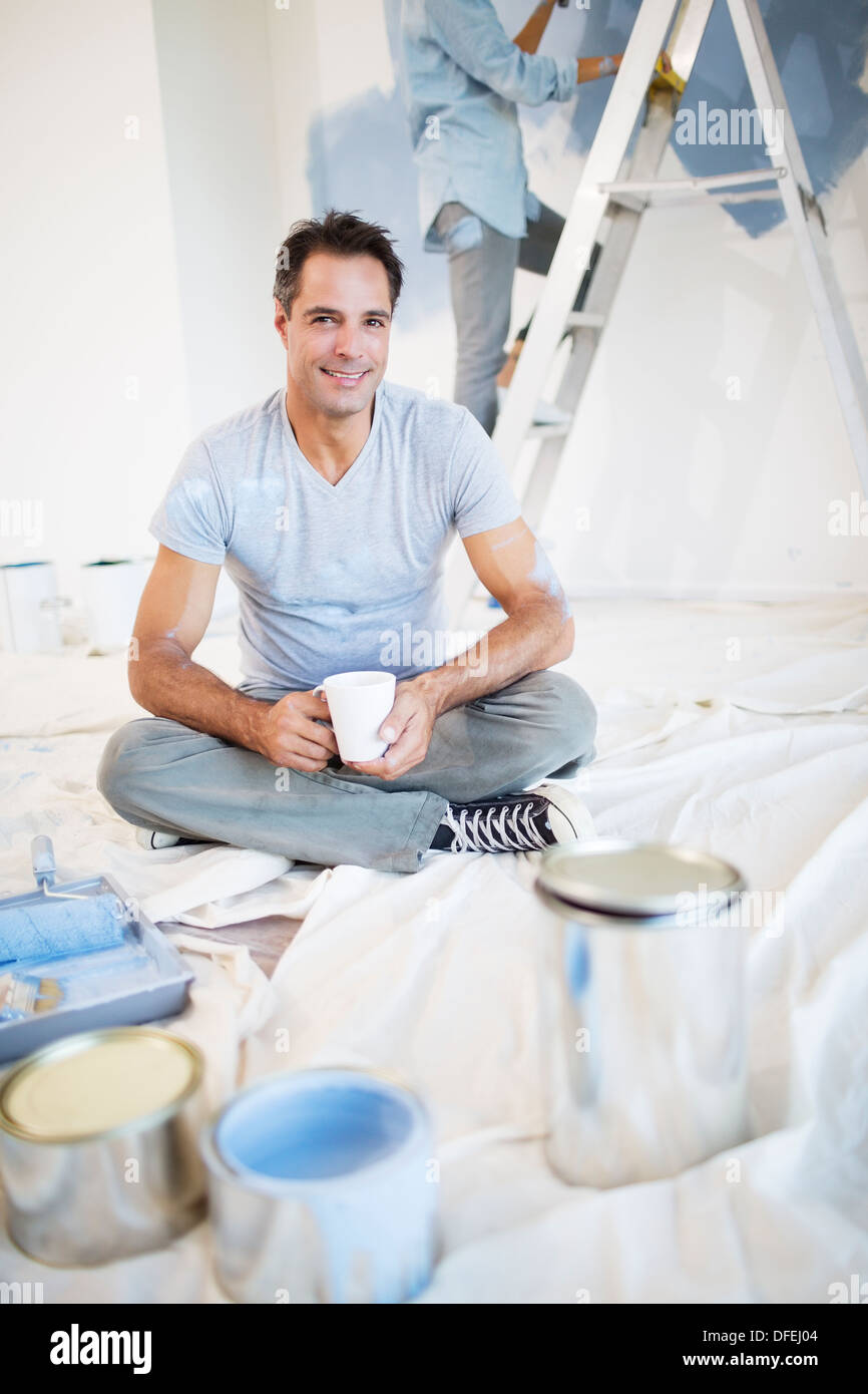 Portrait of smiling man drinking coffee among painting supplies Stock Photo